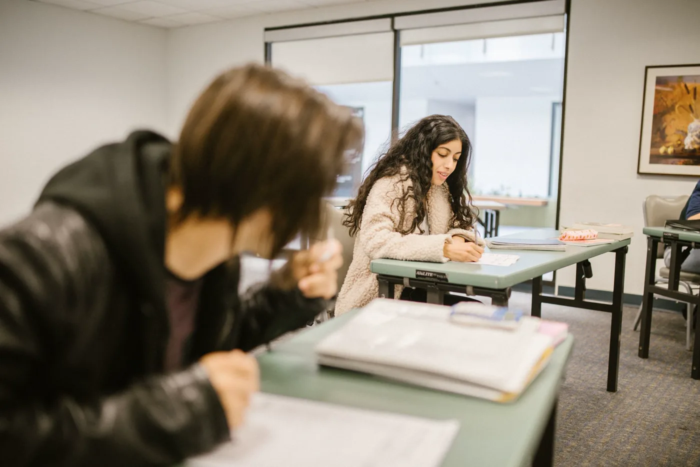 Estudiantes concentrados escribiendo en sus carpetas durante una prueba
