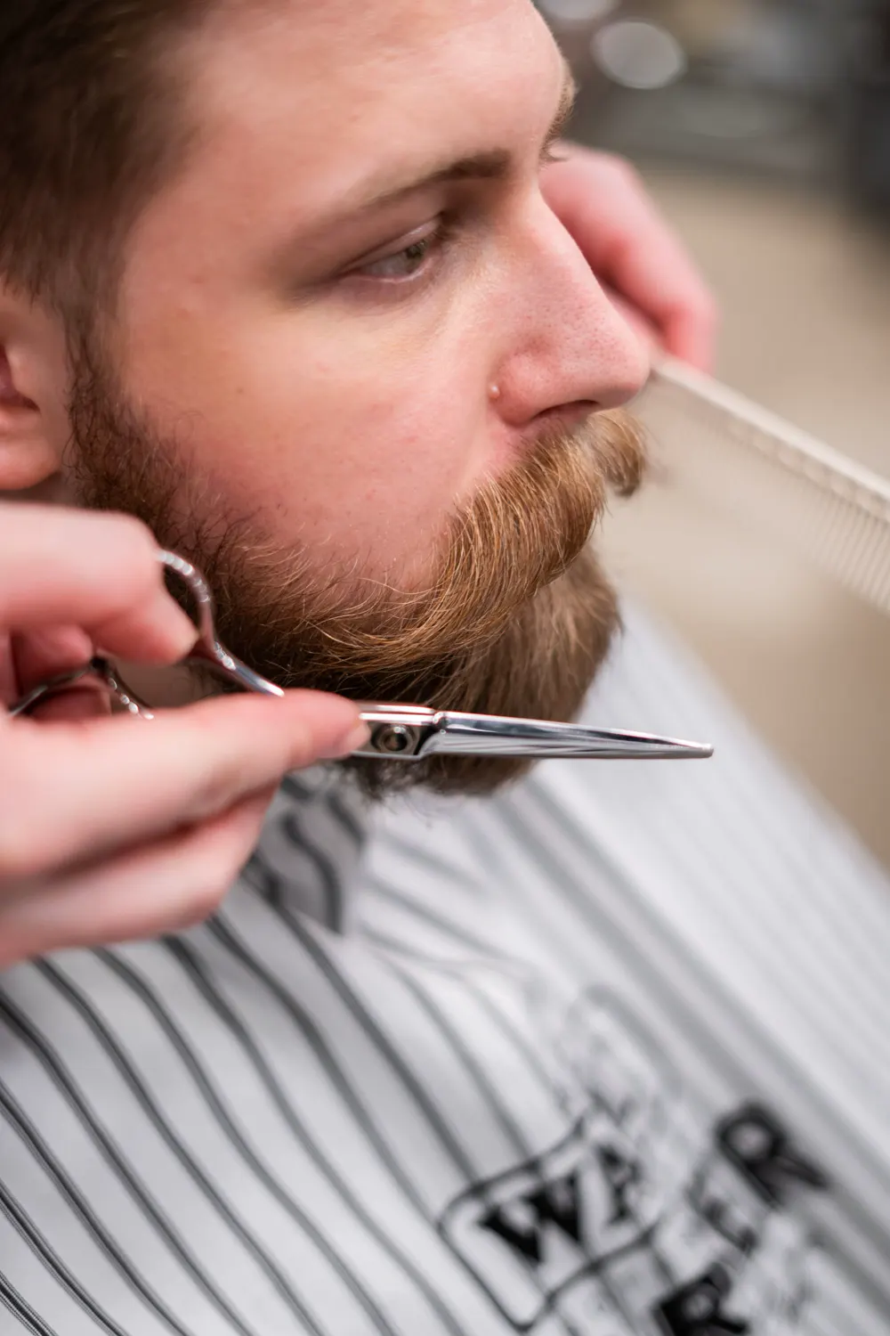 Barbero perfilando la barba con tijera