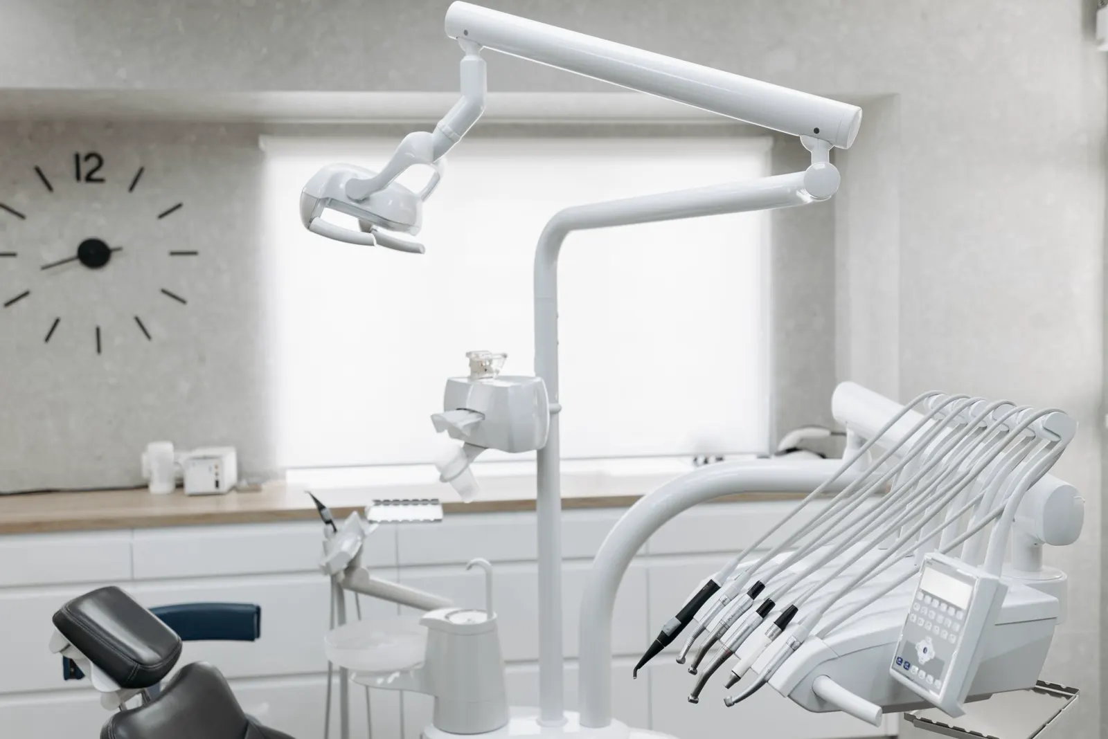 Consultorio dental blanco con sillón, lámpara y reloj de pared