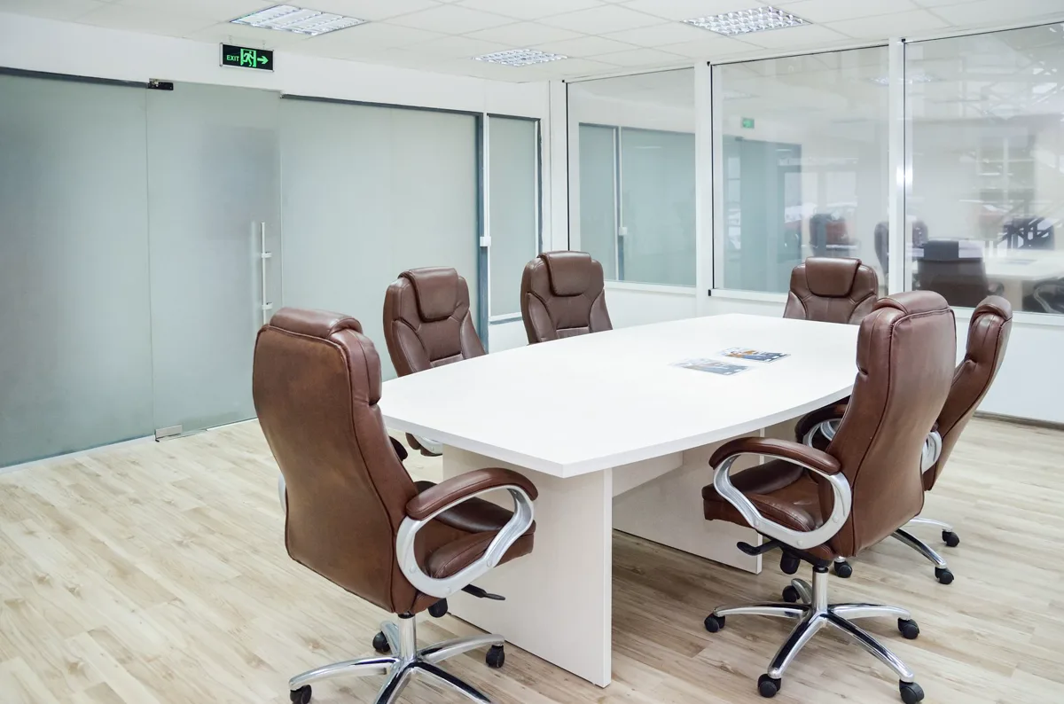 Sala de reuniones luminosa con mesa blanca y sillas de cuero