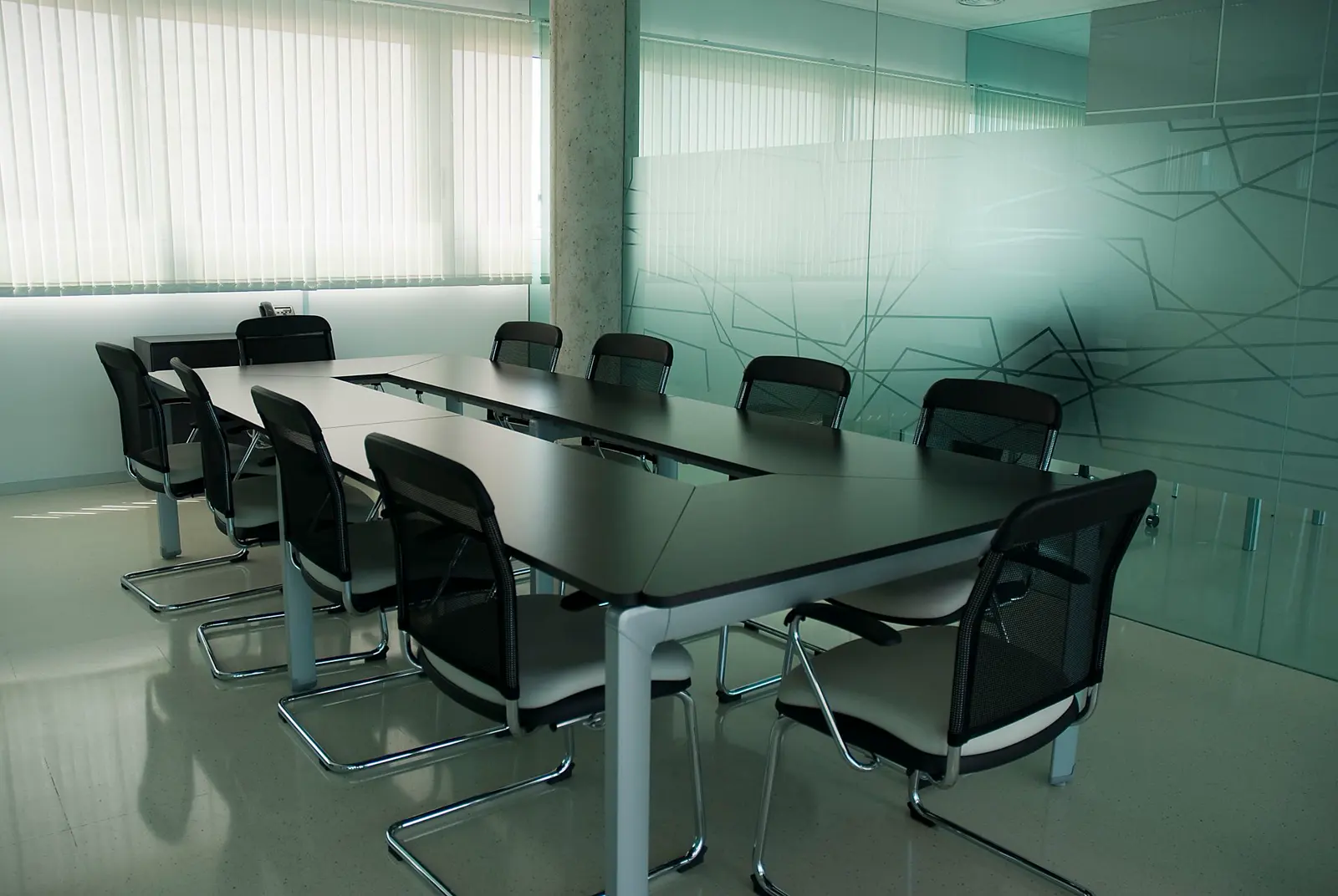 Sala de reuniones luminosa con mesa larga y sillas negras