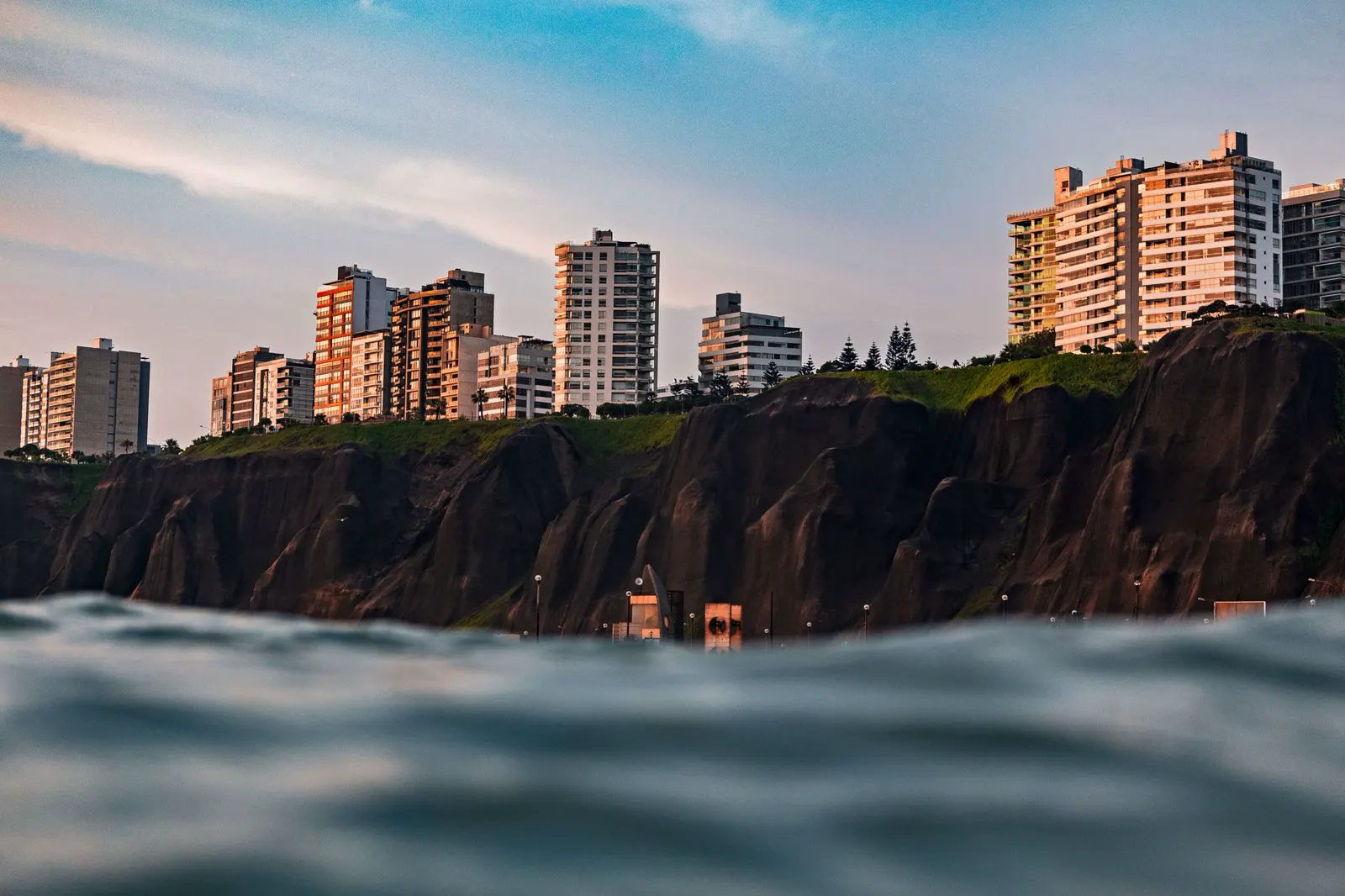 Acantilados de la Costa Verde y edificios al atardecer, vistos desde el mar