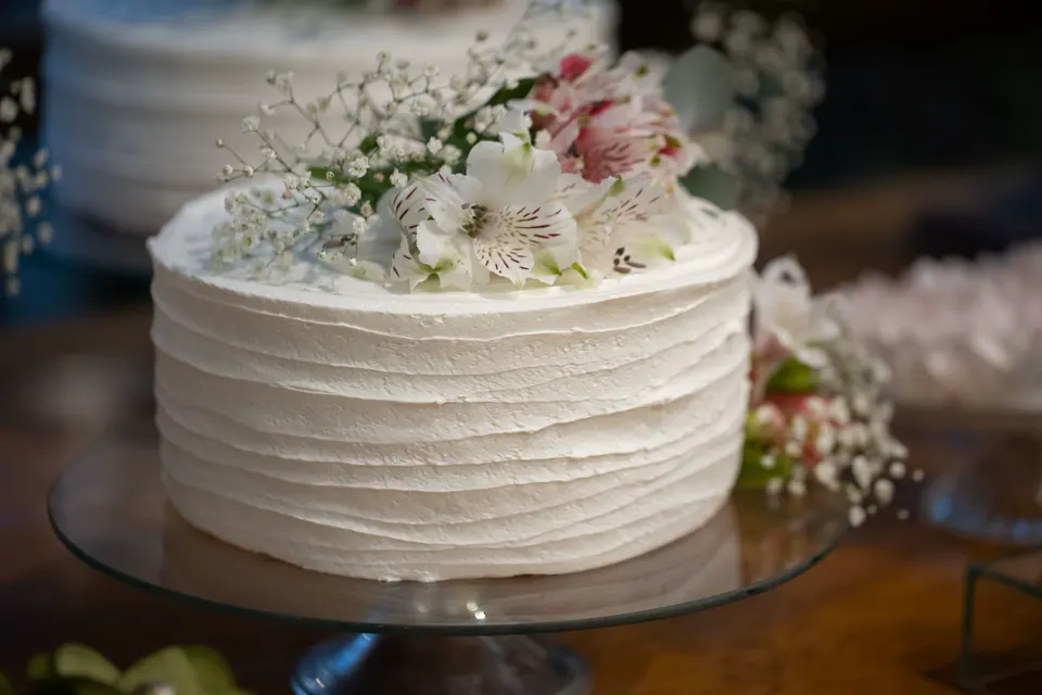 Torta blanca con flores naturales sobre una base de vidrio