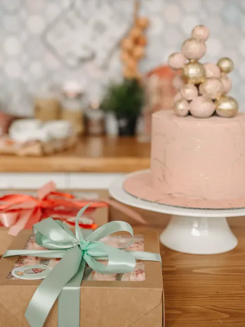 Torta rosada sobre una base, junto a una caja de regalo