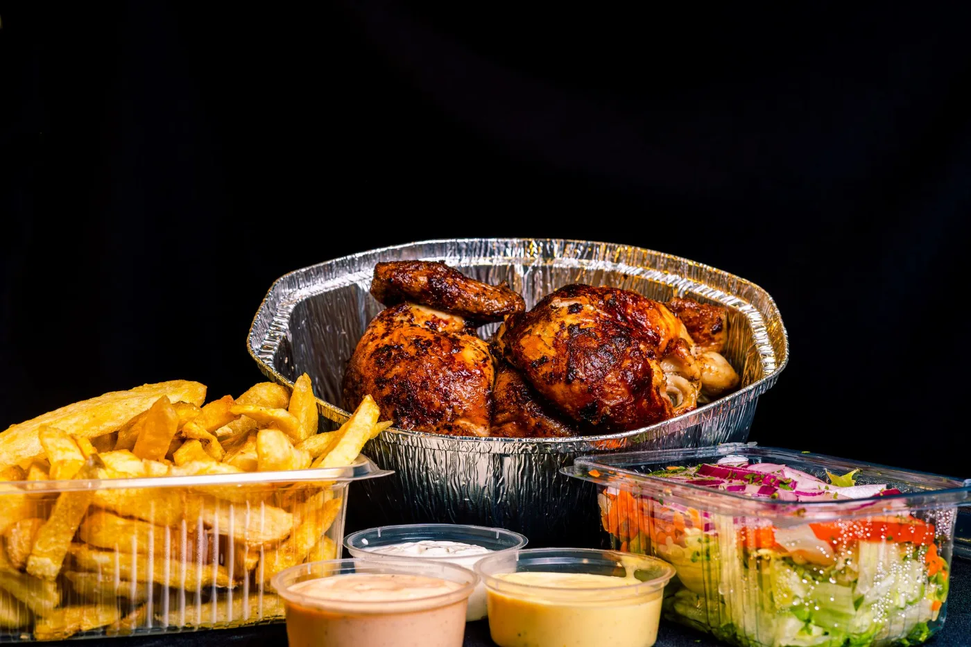 Pollo a la brasa para llevar con papas, ensalada y cremas