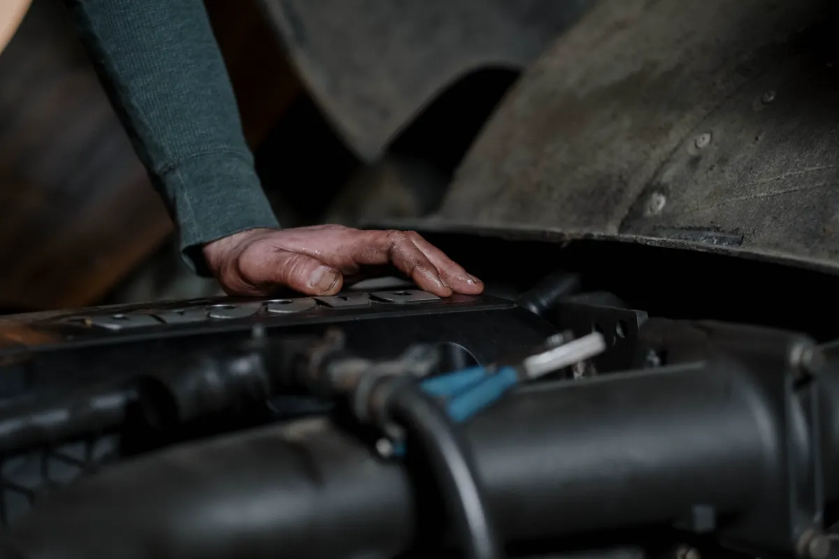 Mano de un mecánico sobre el motor de un auto