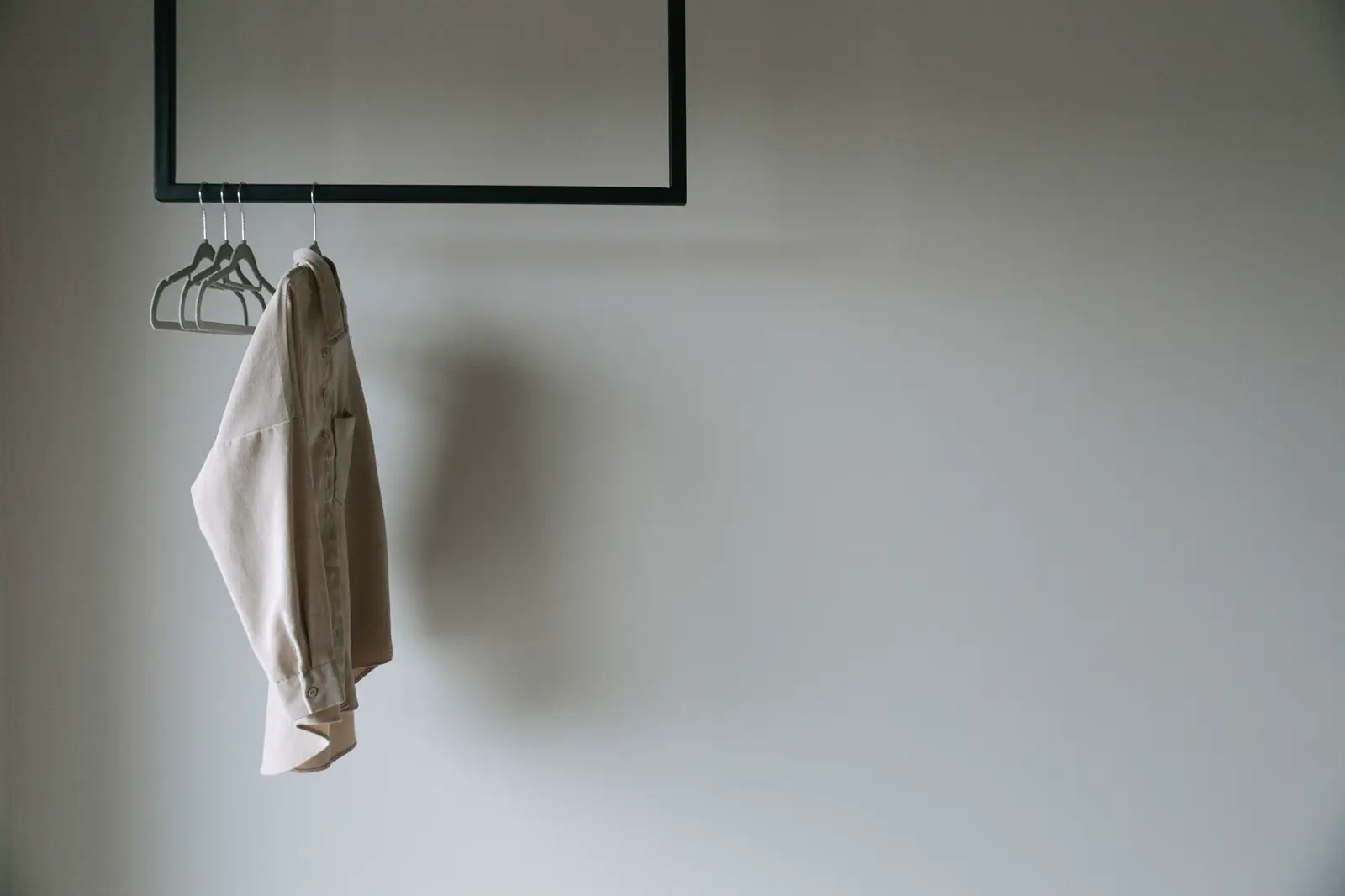Barra negra con una sobrecamisa colgada en una sala blanca y vacía